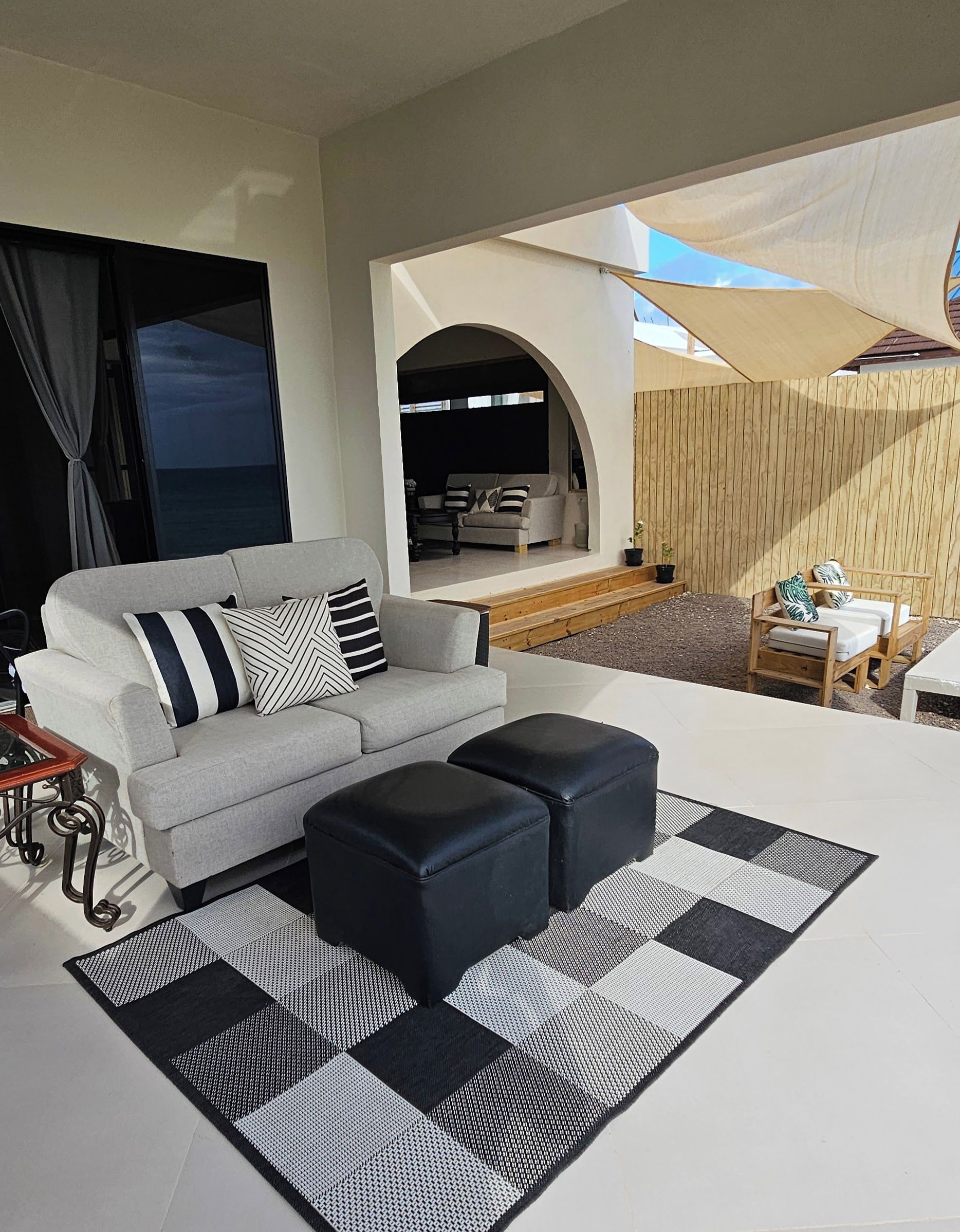 Ein modernes Wohnzimmer mit einer Couch, Poufs und einem karierten Teppich.