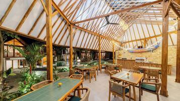 A restaurant with a high wooden ceiling and tables with green cushions.