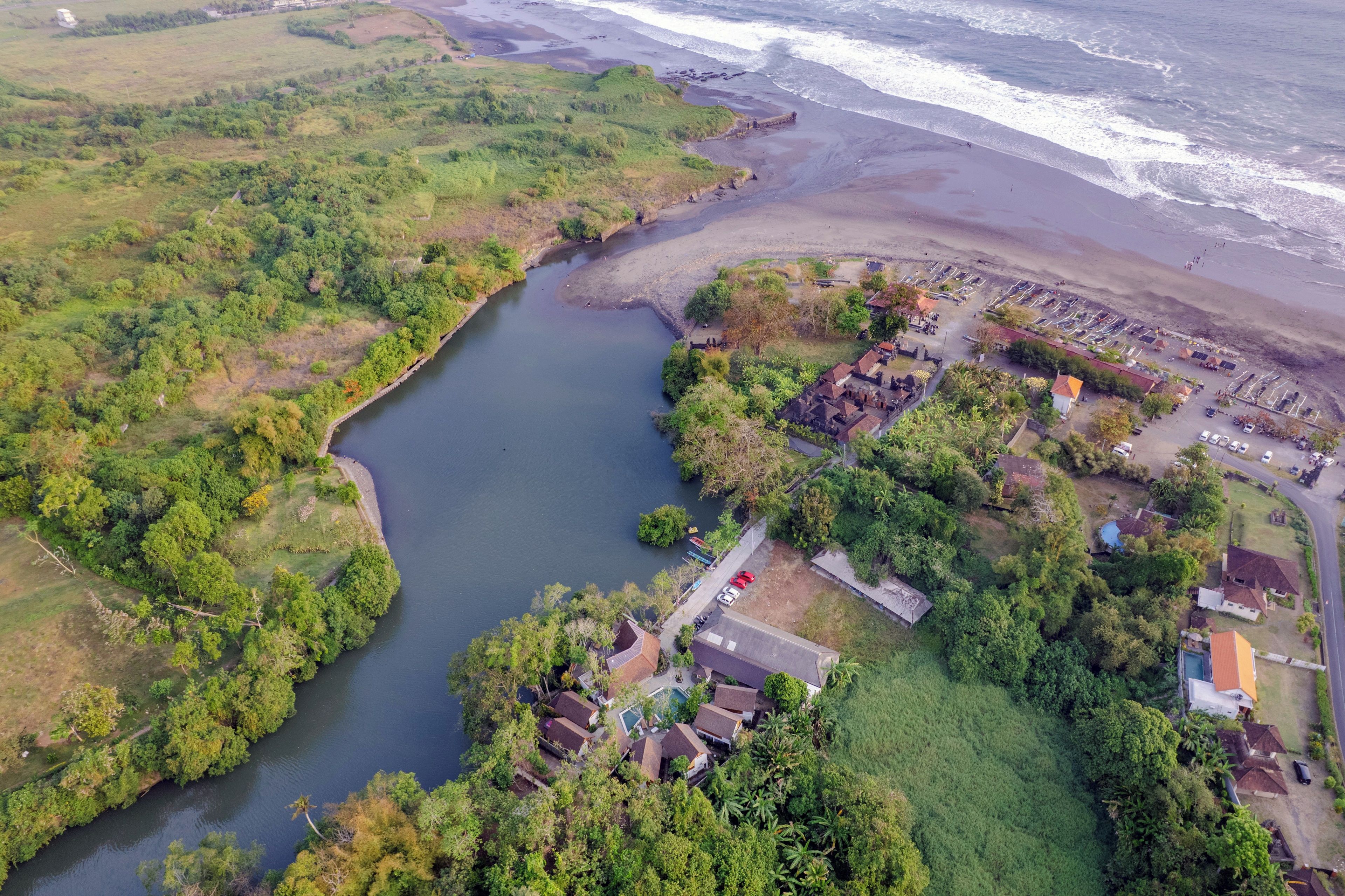 An aerial view of a coastal area with a river, beach, and residential buildings.
