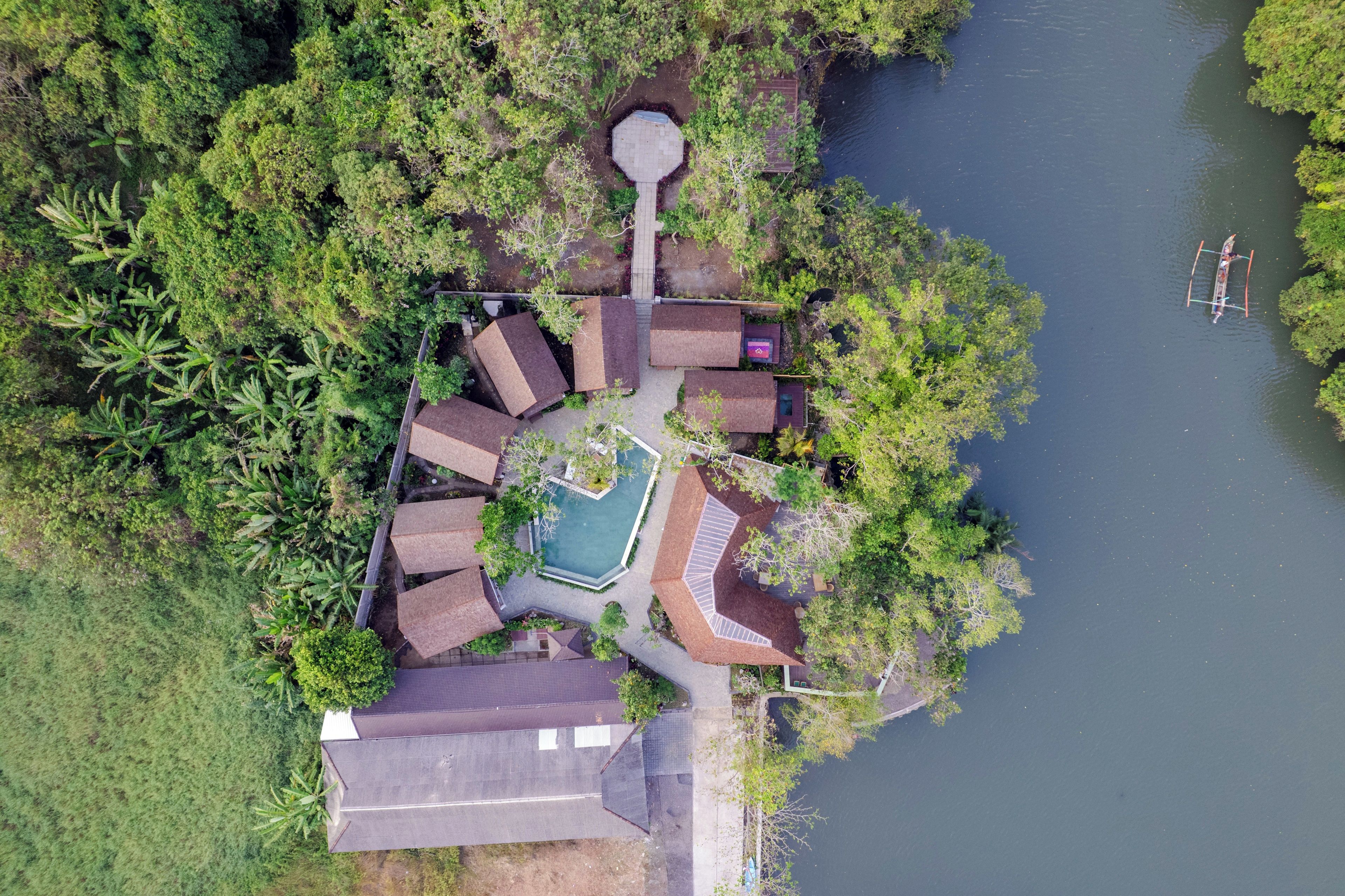 Vista aérea de una propiedad con piscina, varios edificios y un muelle.