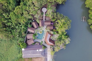 An aerial view of a property with a swimming pool, multiple buildings, and a dock. - Semara Gangga Beach Retreat (Tabanan)