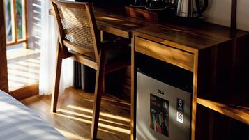 Un escritorio de madera con un refrigerador GEA, una silla y una tetera sobre la mesa.