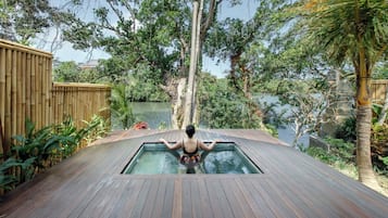 Un jacuzzi en una terraza de madera con vista a un lago y árboles.