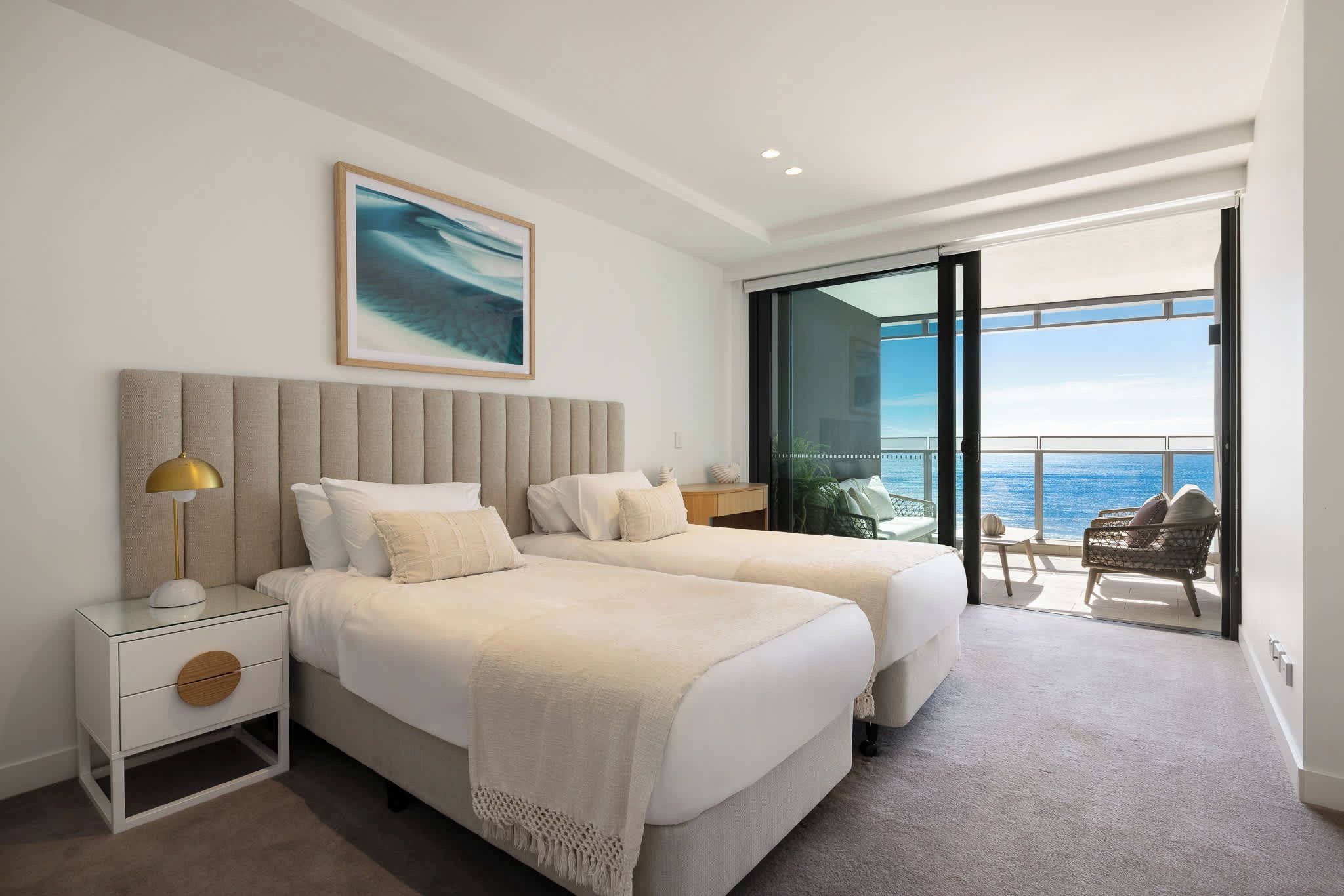 Wake up to ocean views in the second bedroom, with soft coastal styling and balcony access.