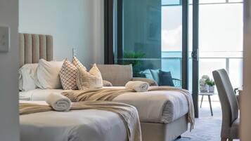 A hotel bedroom with a large bed, multiple pillows, a side table, and a view of the outdoors.