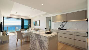 Prepare meals in the contemporary kitchen, with a marble-look island and ocean views beyond the dining area.