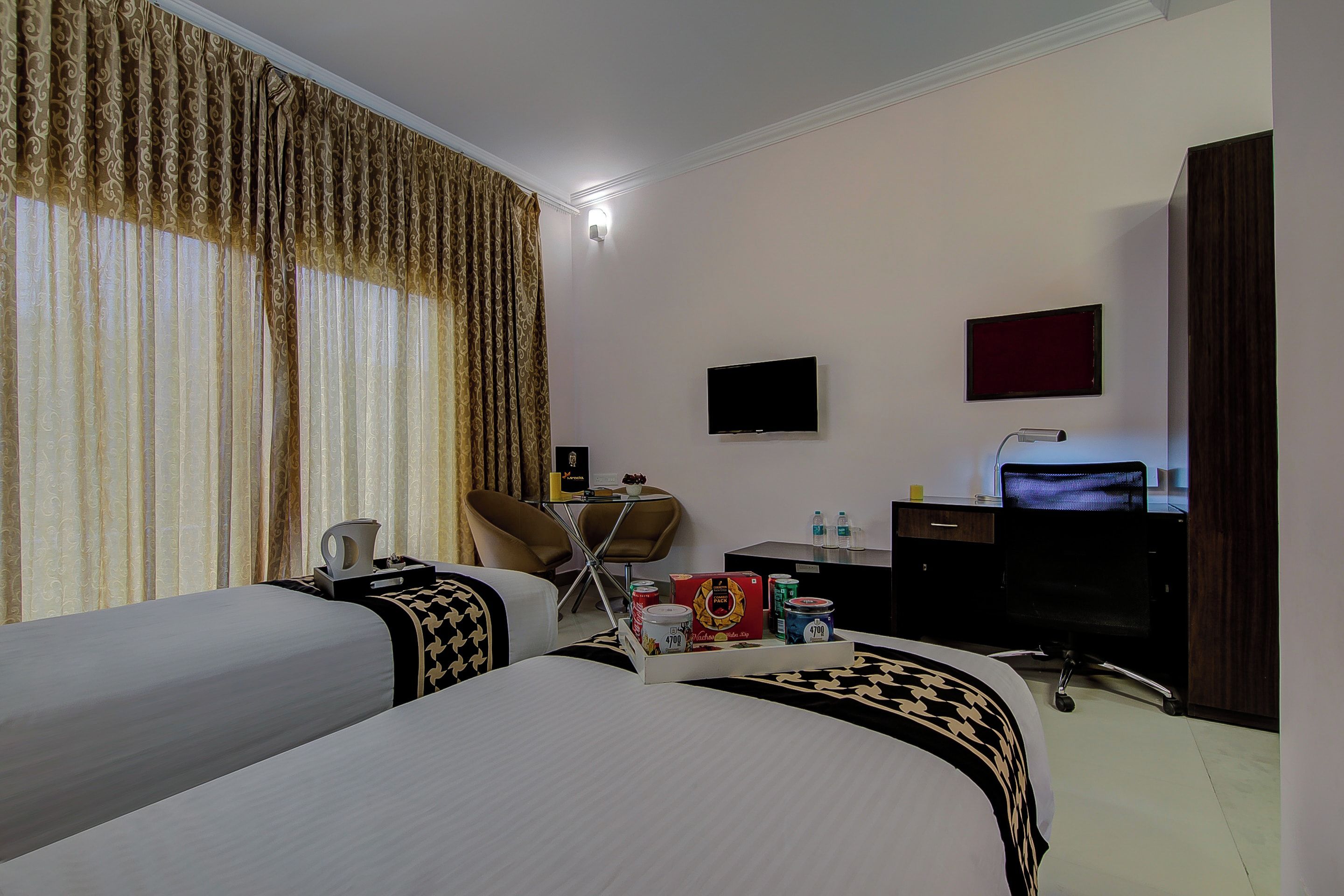 Une chambre d’hôtel avec deux lits, un bureau, une chaise, une télévision et un mini-bar.