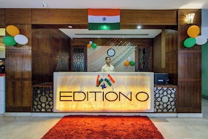 En receptionsdisk med et skilt, der viser 'EDITIONO', og et indisk flag hængende over den.