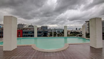 A rooftop swimming pool with a view of surrounding buildings.