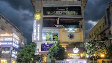 Un edificio de varios pisos con diversos establecimientos comerciales en la planta baja, incluyendo un restaurante y un hotel.
