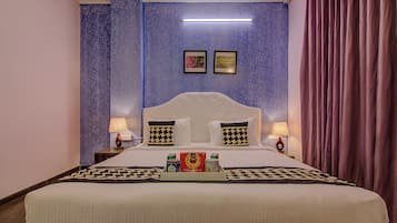 A hotel room with a large bed, two bedside lamps, a tray with snacks, and a wall with a leaf pattern.
