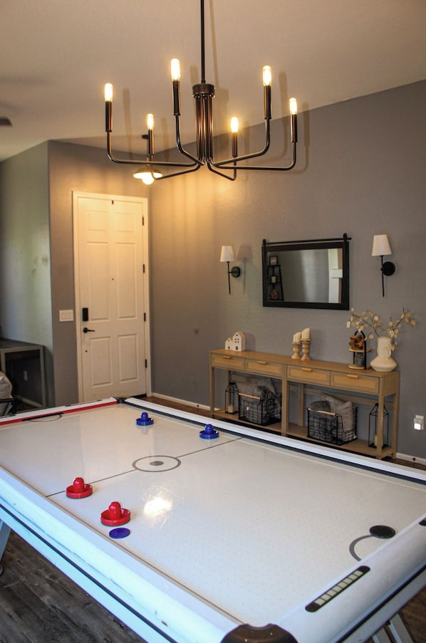 A room with a foosball table, a door, a mirror, wall sconces, and a cabinet with decorative items. - Inside Anthem master plan community. 8 minute drive to TSMC. Close to I-17! (Phoenix)