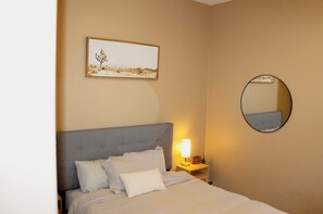 A hotel room with a bed, a bedside lamp, a framed picture on the wall, and a round mirror. - Inside Anthem master plan community. 8 minute drive to TSMC. Close to I-17! (Phoenix)