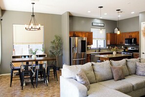 Una cocina moderna con una isla central, armarios de madera, electrodomésticos de acero inoxidable y una zona de comedor con sofá y sillas.