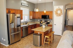 A modern kitchen with stainless steel appliances, wooden cabinets, and a central island with stools. - Inside Anthem master plan community. 8 minute drive to TSMC. Close to I-17! (Phoenix)