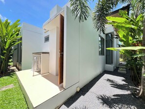 Ein modernes Haus mit weißer Fassade, einer Holztür und einem kleinen Fenster.