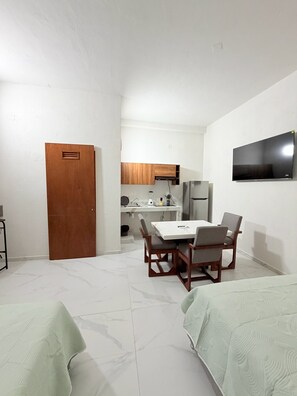 A compact living space with a dining area, kitchenette, and a television mounted on the wall. - Cathedral Centro Histórico D18 (Guadalajara)