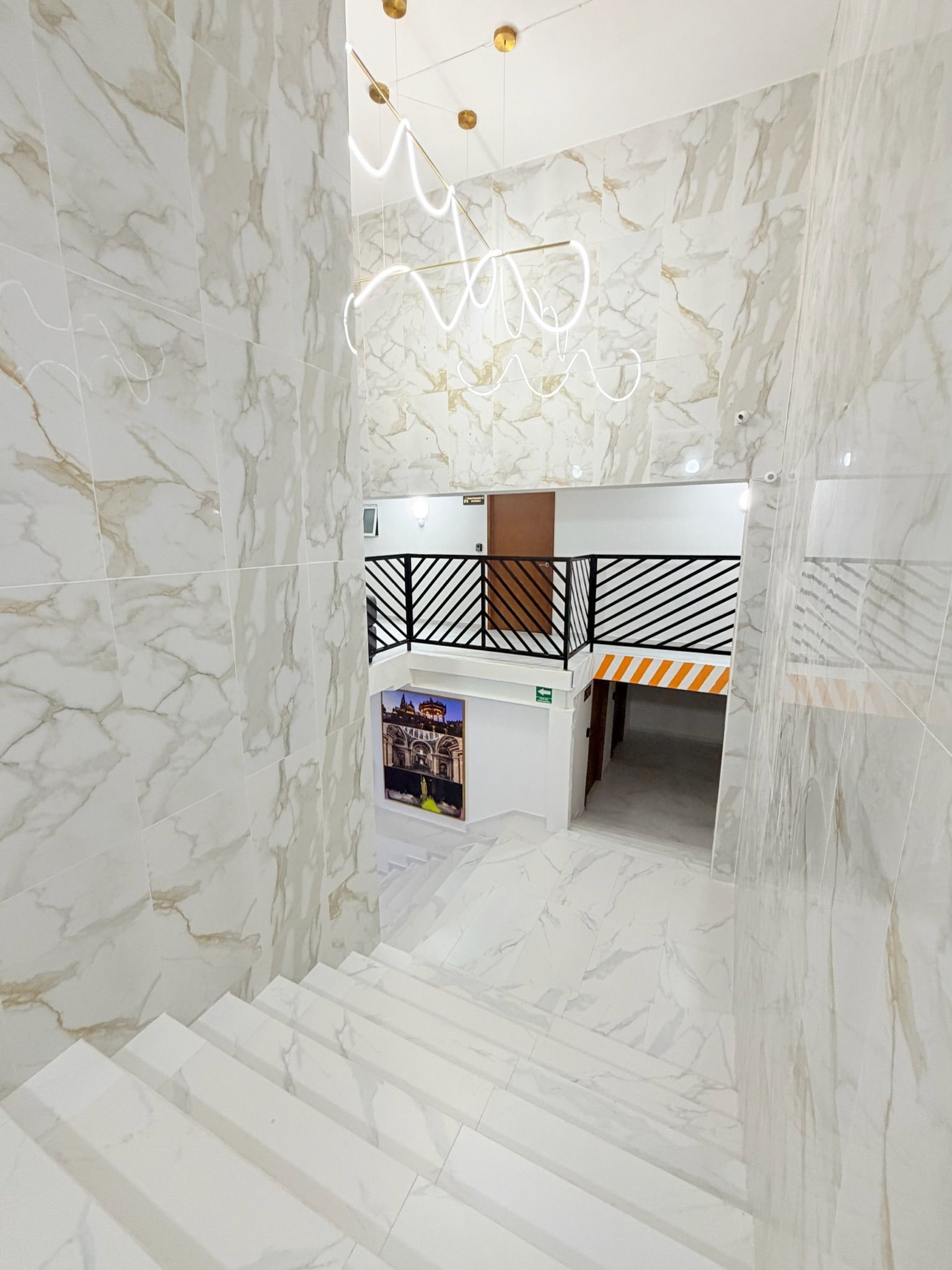 A hotel lobby with marble walls, a staircase, and a bunk bed area.