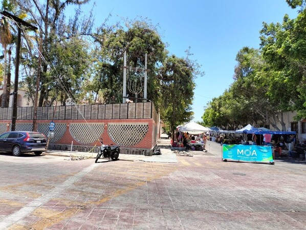 Una calle pavimentada con un muro de ladrillo, una motocicleta e un estandarte azul con texto.