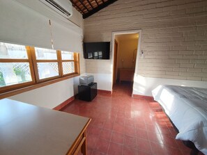 Een kamer met een bed, een bureau, een aan de muur bevestigde televisie en een raam met uitzicht.