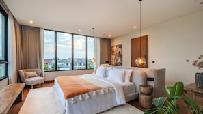 A modern bedroom with a large bed, a seating area, and a view of the city. - Five Palms Villa by Elite Havens  (Mengwi, Badung)