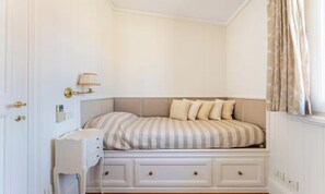 Een slaapkamer met een bed, nachtkastje en een wandlamp.