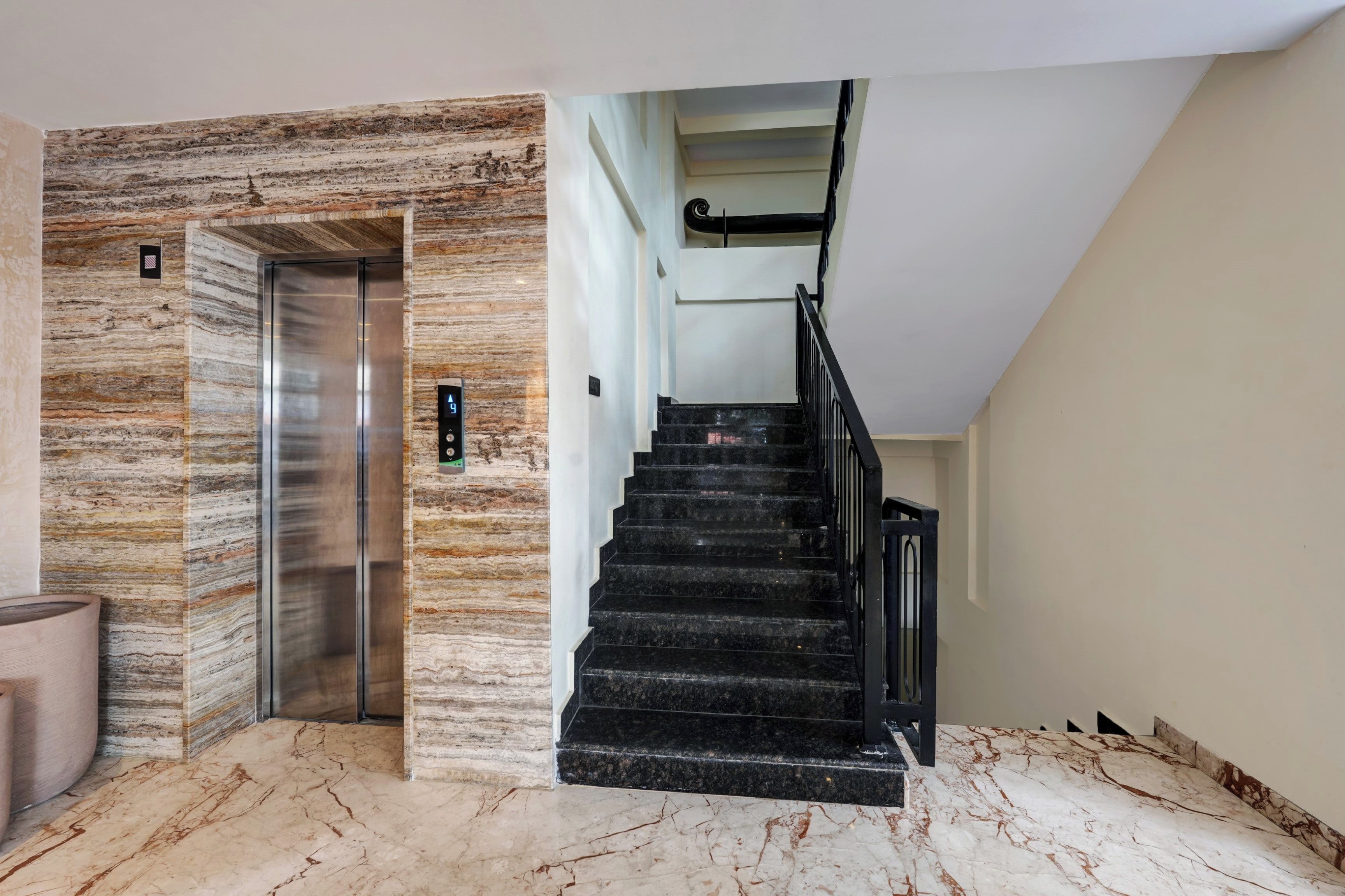 Un interior moderno con una escalera de mármol, un ascensor y un diseño minimalista.