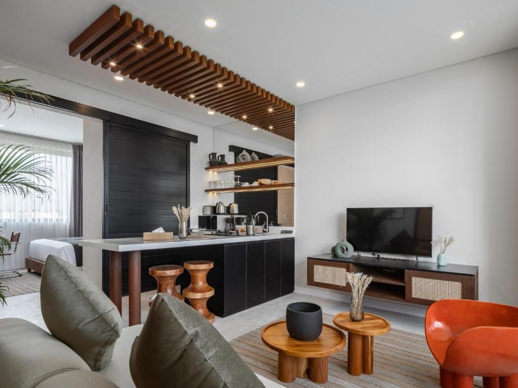 A modern living room with a kitchen area, a flat-screen TV, and a sofa.