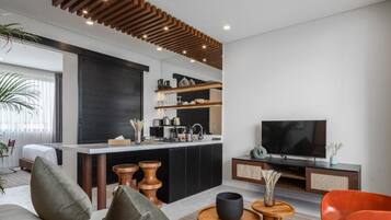 A modern living room with a kitchen area, a flat-screen TV, and a sofa.