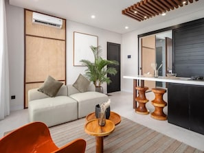 A modern living room with a sofa, a coffee table, and a dining area with a counter. - AKA Seseh Living (Badung)