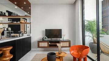 A modern living room with a TV, wooden furniture, and a large window.