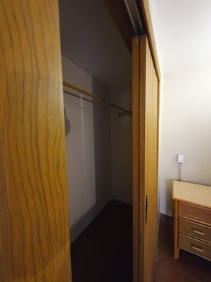 A room with a wooden wardrobe, a small desk, and a wall socket. - Sandy Shores 4A y 4B (La Paz)