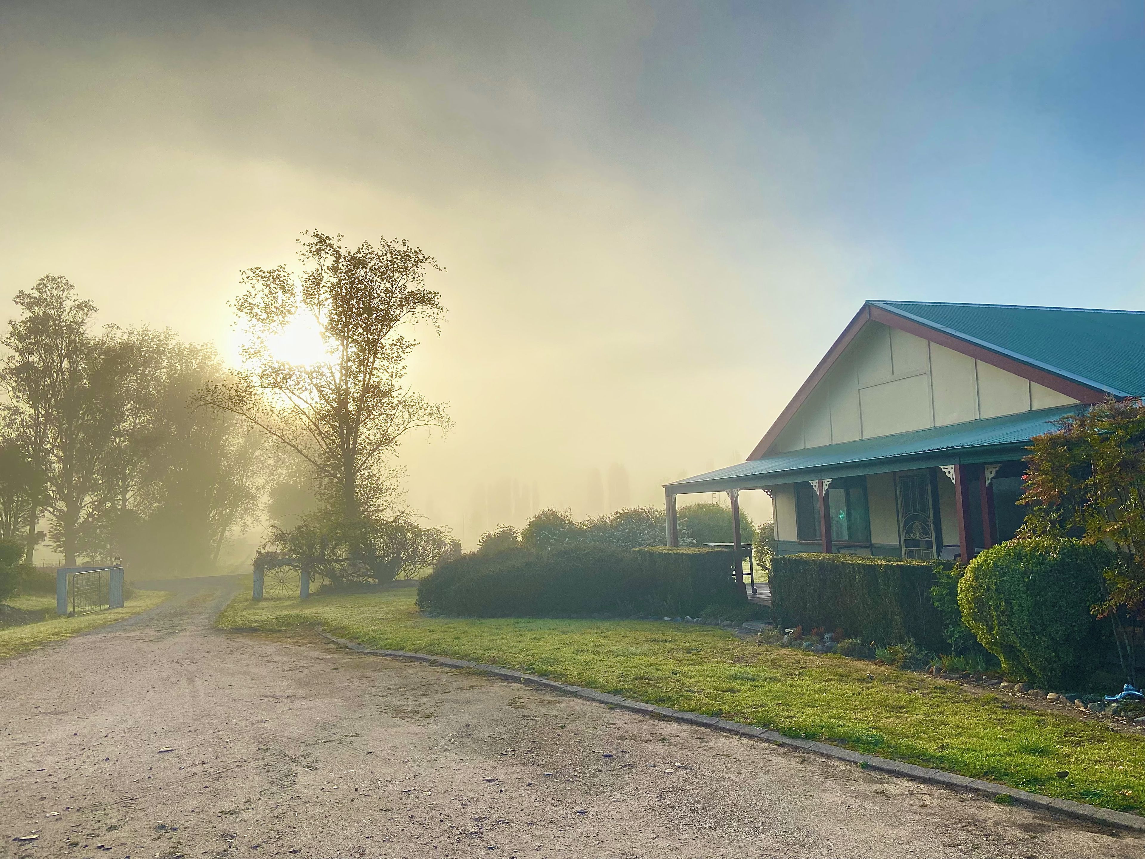 Een landweg die leidt naar een huis met een veranda en een blauw dak.