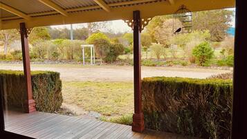 A covered outdoor area with a wooden deck, a pergola structure, and a view of a landscaped garden with various plants and a pathway.
