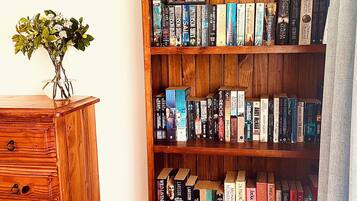 Une bibliothèque en bois remplie de livres, une commode en bois avec des tiroirs et un vase avec des fleurs posé sur le dessus.