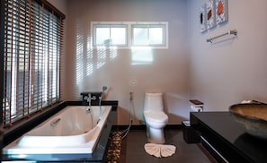 Een moderne badkamer met een badkuip, toilet en een raam.