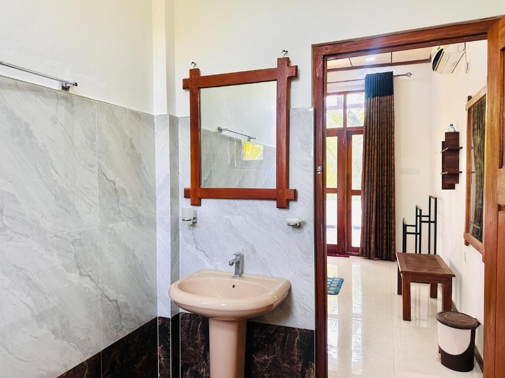 A bathroom with a sink, mirror, and a wooden door leading to another room.