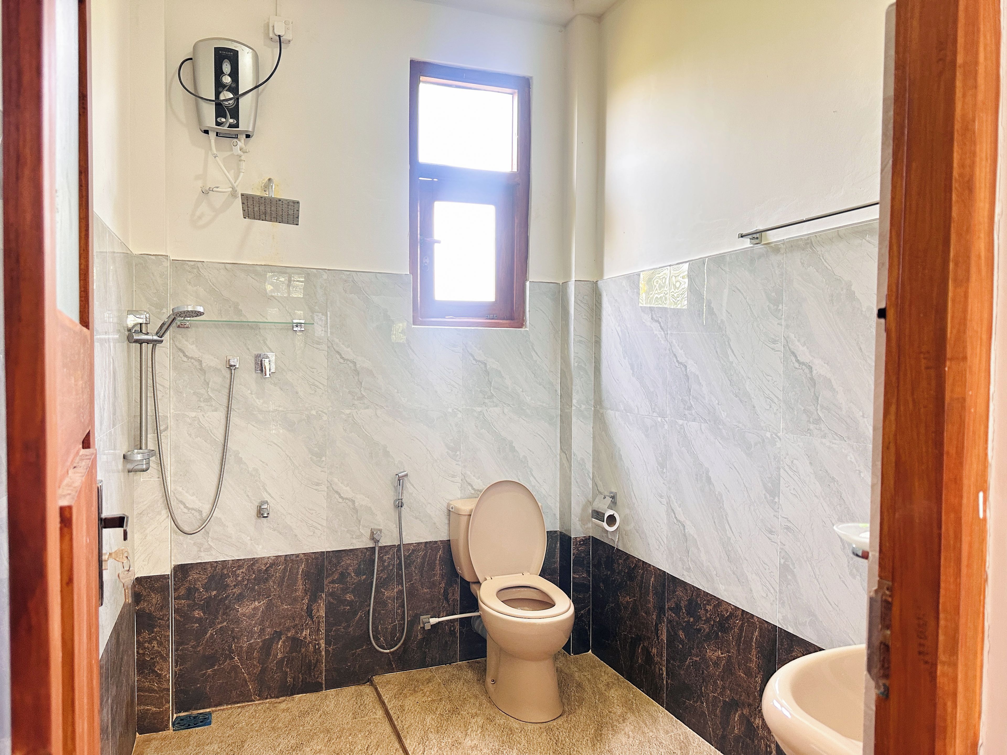 Un baño con inodoro, ducha y ventana.