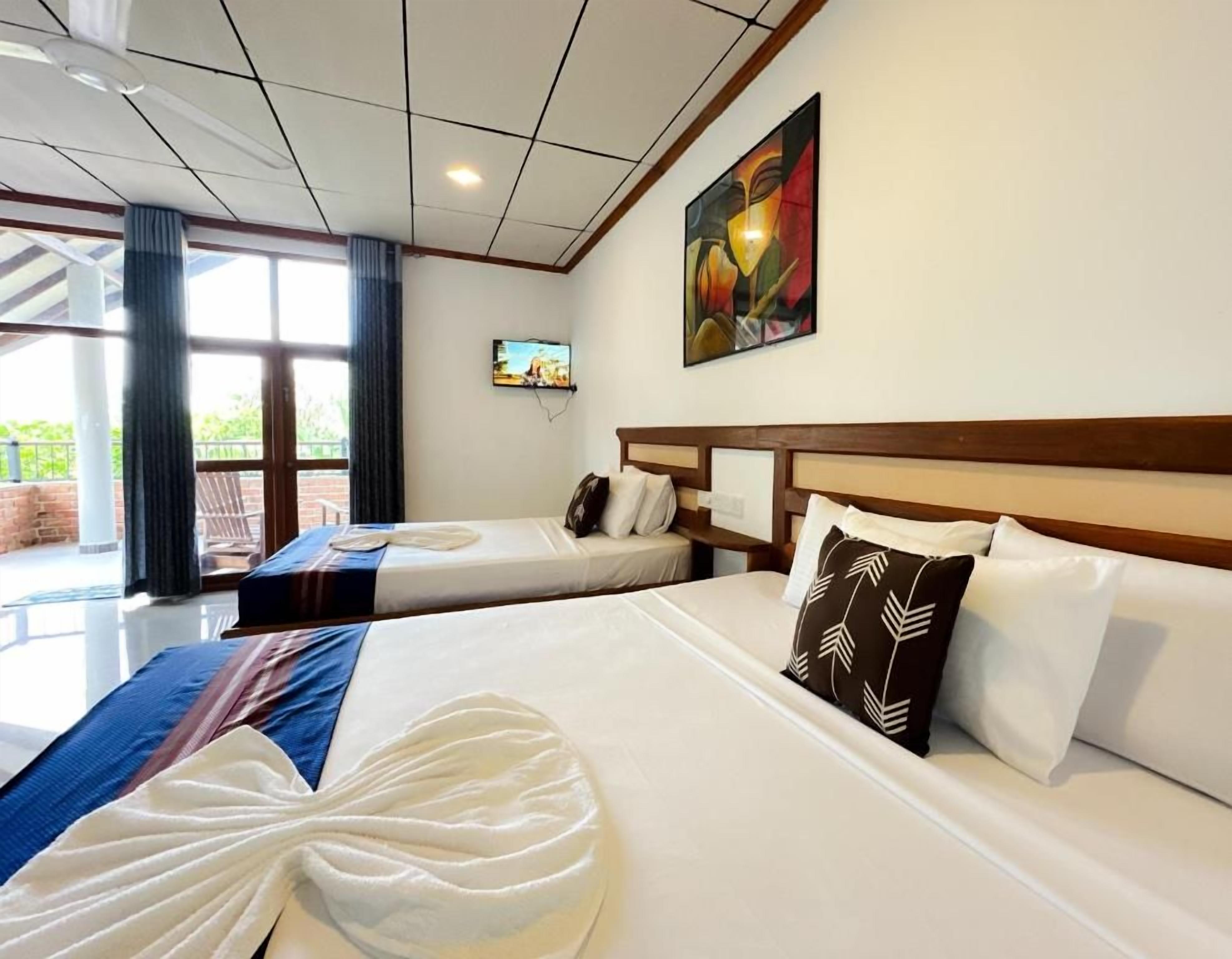 A hotel room with two beds, a painting on the wall, and a television.