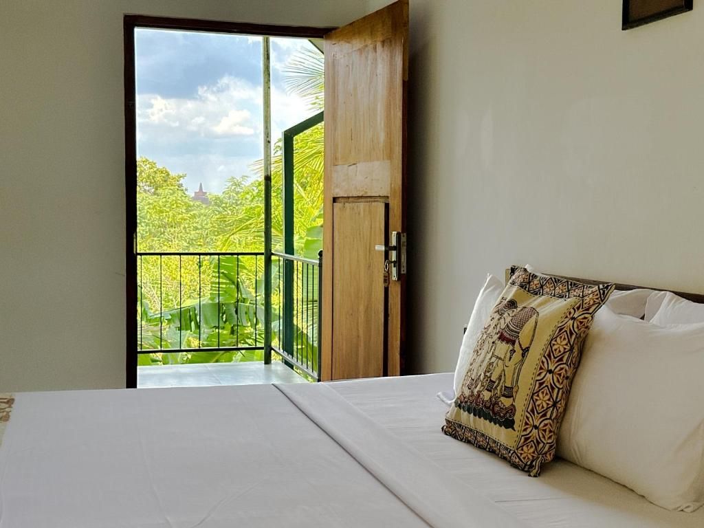 A bedroom with a bed, a window, and a view of greenery outside.