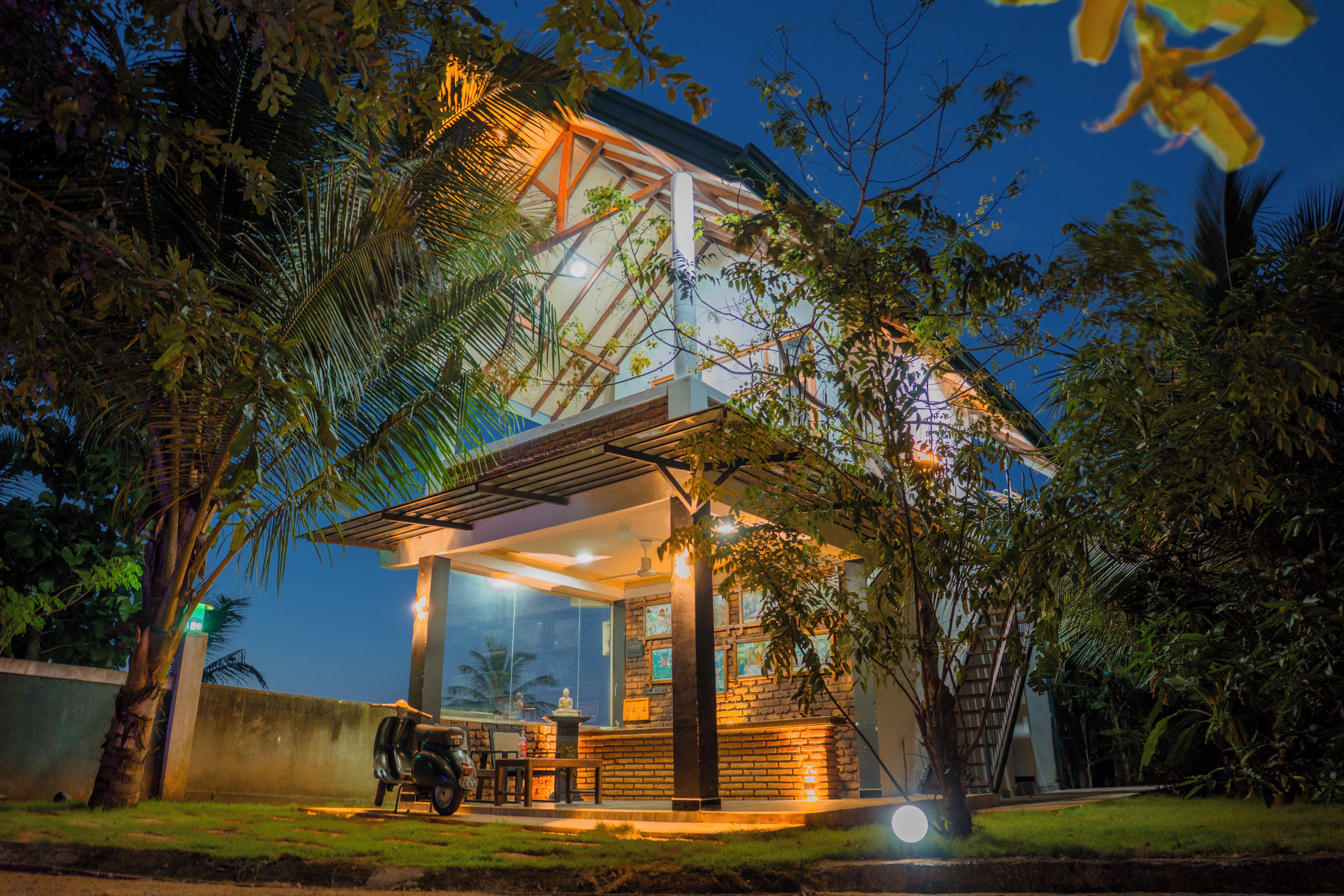A building with a covered patio, a statue, and a scooter parked outside.