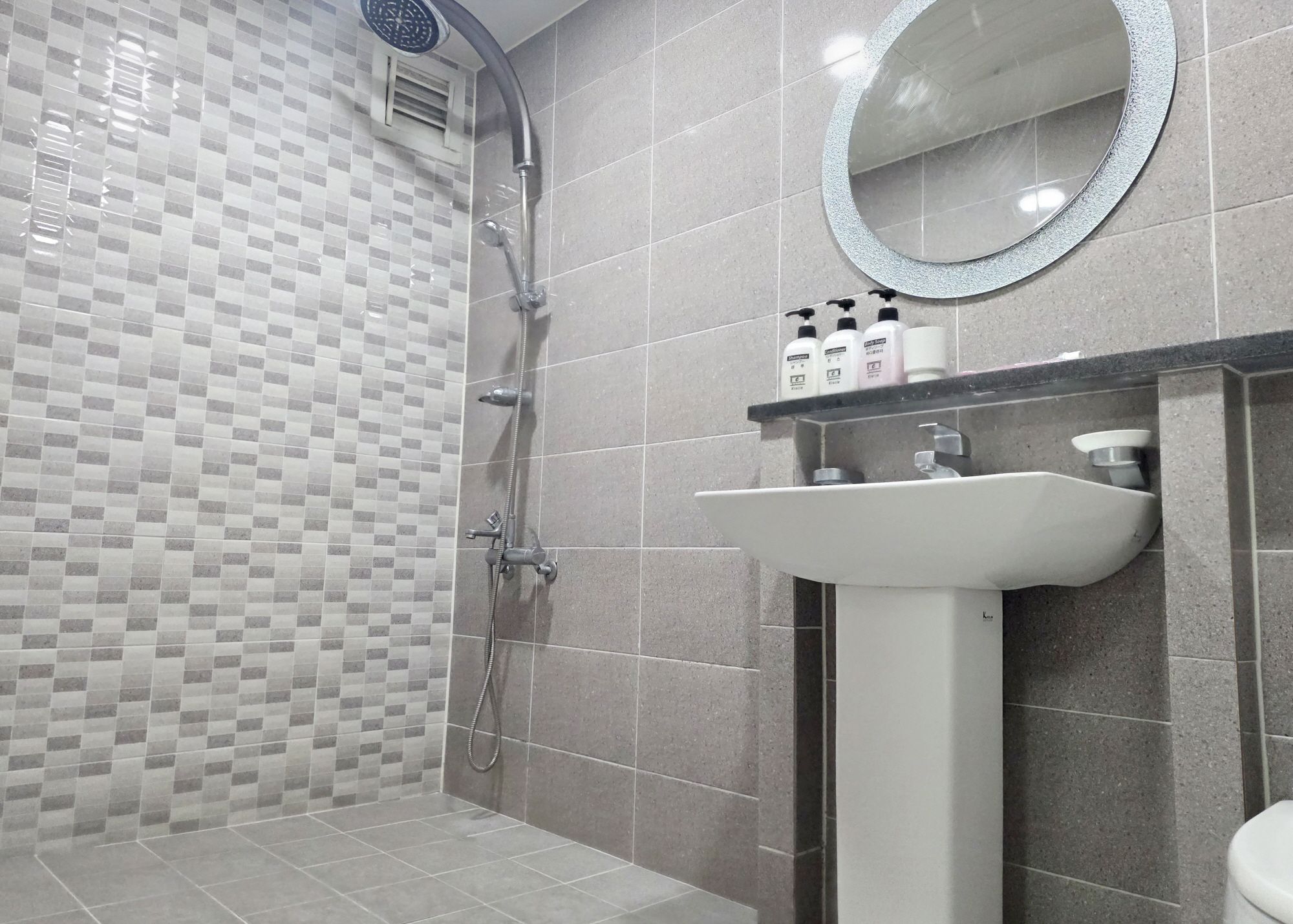 Un baño con ducha, lavamanos y espejo.