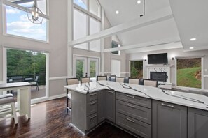 A modern kitchen with a large island, built-in appliances, and a balcony with outdoor seating. - Etowah Overlook (Dahlonega)