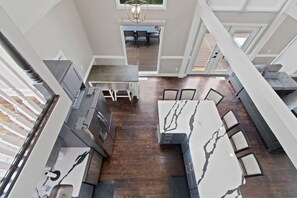 A modern kitchen with a marble countertop, dark wooden flooring, and a dining area with a table and chairs. - Etowah Overlook (Dahlonega)