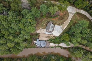 Luchtbeeld van een bezit met een huis, omringd door dichte bomen en een gebogen betonnen pad.