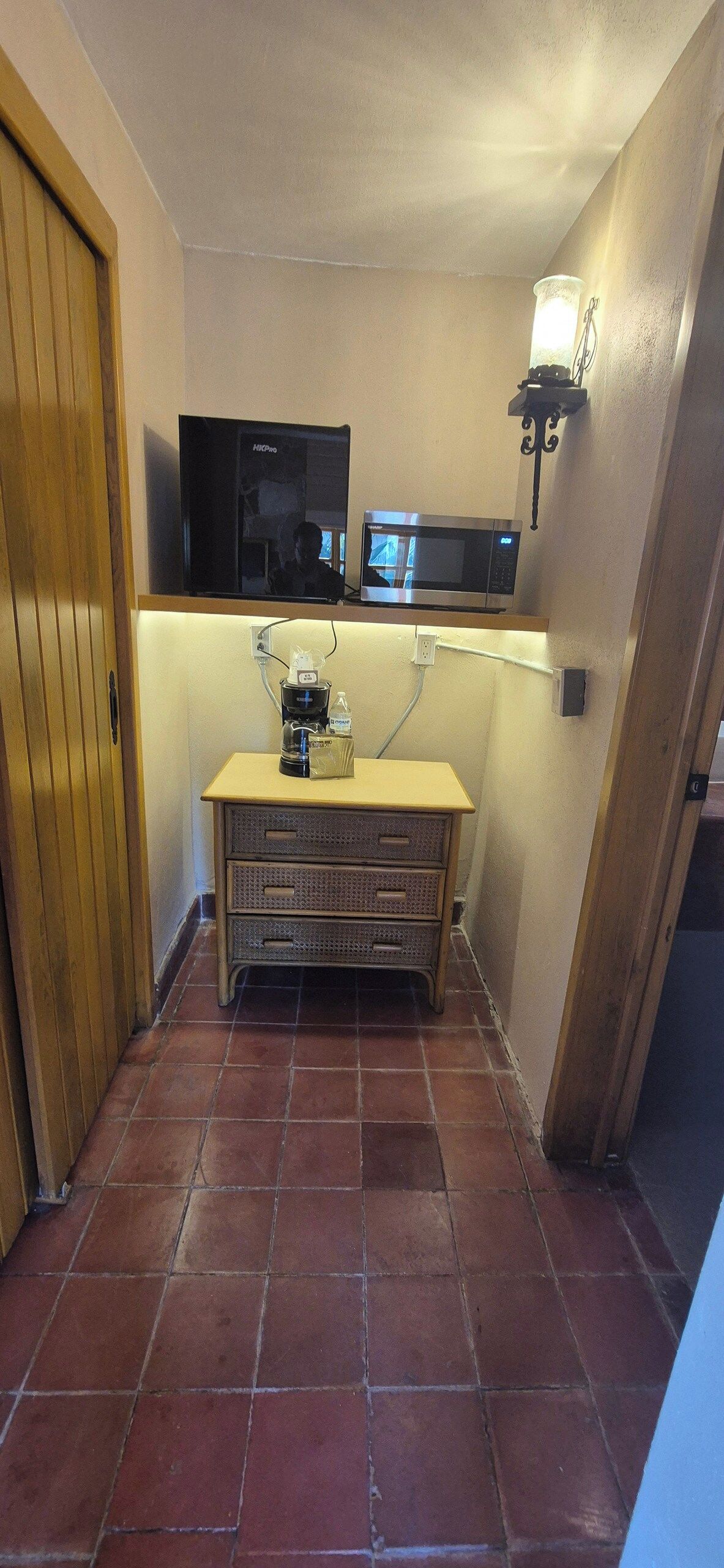 A compact kitchen with a microwave, coffee maker, and a small cabinet.