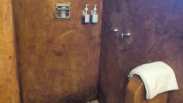Un box de ducha con piso de azulejos, un cabezal de ducha manual y un perchero para toallas.