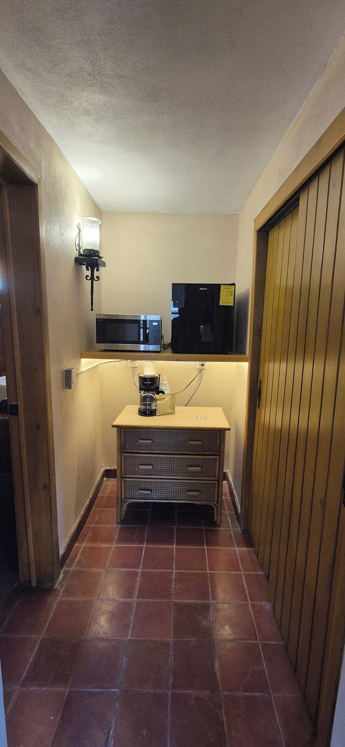 A compact kitchen with a microwave, coffee maker, and a small refrigerator.