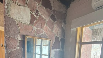 A room with a stone wall, a wooden desk, a chair, and a window.