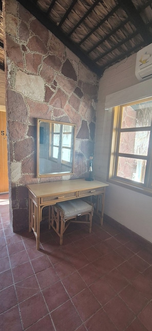 Ein Zimmer mit Steinwand, Holztisch, Stuhl und Fenster.